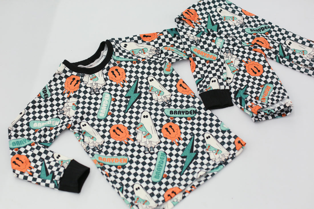 personalized halloween PJ's that have ghosts and skateboards and jack-o-lanterns on a black and white checkered background and black cuffs.