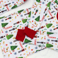 little boys wearing personalized Christmas pajamas featuring classic nutcracker images along with kid's name on white material and red cuffs.