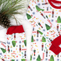 little boys wearing personalized Christmas pajamas featuring classic nutcracker images along with kid's name on white material and red cuffs.