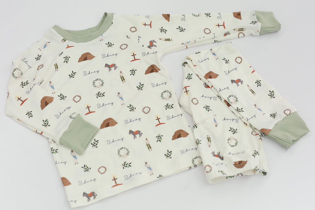 personalized He is Risen Easter PJs with Biblical Easter images on a white stretchy knit fabric, perfect for babies toddlers and big kids.