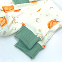 personalized fall pajamas for little boys that have orange cartoon pumpkins and child's name in light brown letters on ivory fabric with green cuffs.
