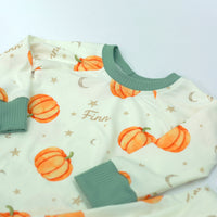 personalized fall pajamas for little boys that have orange cartoon pumpkins and child's name in light brown letters on ivory fabric with green cuffs.