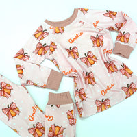 personalized Halloween nightwear for kids, pink pajamas with pumpkins and bows and little girls name, with pink cuffs.