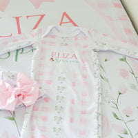 Baby outfit with floral design and matching headband on a pink floral background