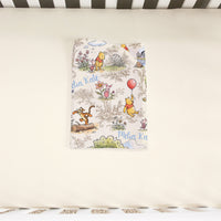 A Winnie the Pooh themed bedding set with illustrations of the characters and the text "Melinda Kate" printed on it.