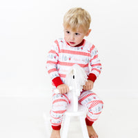 Little boy wearing personalized Modern Nutcracker Ballet for little boys with minimalistic images from the Nutcracker Ballet and his name with red checkered stripe pattern on white background and red cuffs.