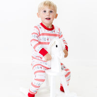 Little boy wearing personalized Modern Nutcracker Ballet for little boys with minimalistic images from the Nutcracker Ballet and his name with red checkered stripe pattern on white background and red cuffs.