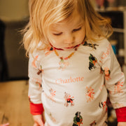little girl wearing kids custom pajamas with christmas puppies in boys and wreathes with their name, red cuffs