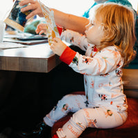 little girl wearing kids custom pajamas with christmas puppies in boys and wreathes with their name, red cuffs