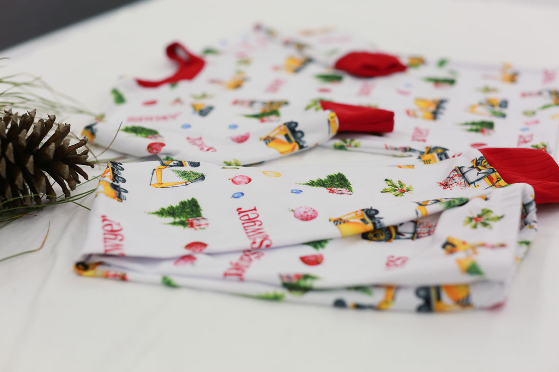 Construction Christmas Pajamas laying on table near Christmas decorations.