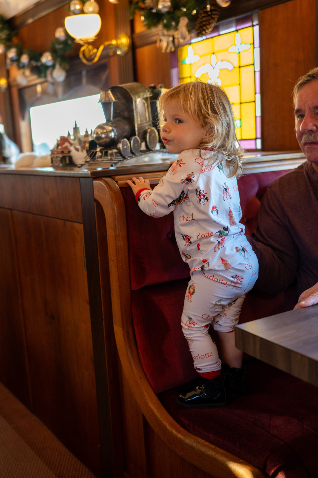 little girl wearing kids custom pajamas with christmas puppies in boys and wreathes with their name, red cuffs