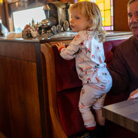 little girl wearing kids custom pajamas with christmas puppies in boys and wreathes with their name, red cuffs