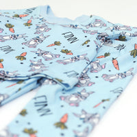 boys easter personalized pajamas featuring his name, hip easter bunnies in glasses and hats, and cartoon carrots on light blue stretchy knit fabric.