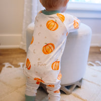 Baby wearing Autumn PJ's with orange pumpkins and baby's name on white background with green cuffs