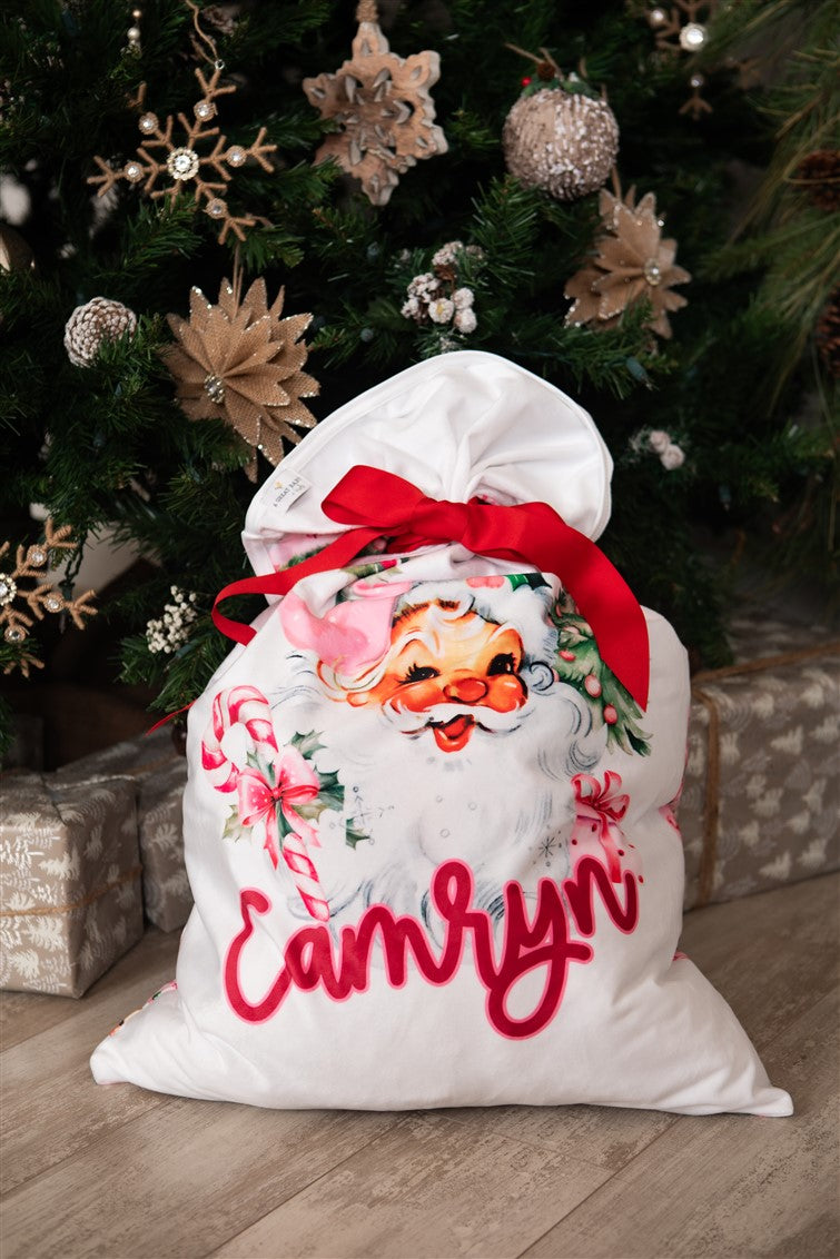 Minky fabric Christmas pillowcase for girls with vintage Santa face and pink accents and kid's name in red script font. Red ribbon tied on the top to make it into a gift sack.