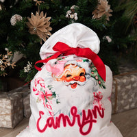 Minky fabric Christmas pillowcase for girls with vintage Santa face and pink accents and kid's name in red script font. Red ribbon tied on the top to make it into a gift sack.