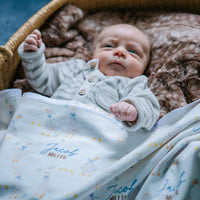 soft white baby blanket with geese and personalized name draped across baby boy in bassinet