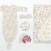 Flat lay of Wildflowers Take Me Home Set with personalized baby gown, floral blanket, bow, hat, and name disc