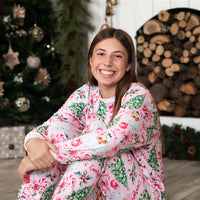 Adult sitting in front of the fire place wearing her Pink Santa Pajamas.