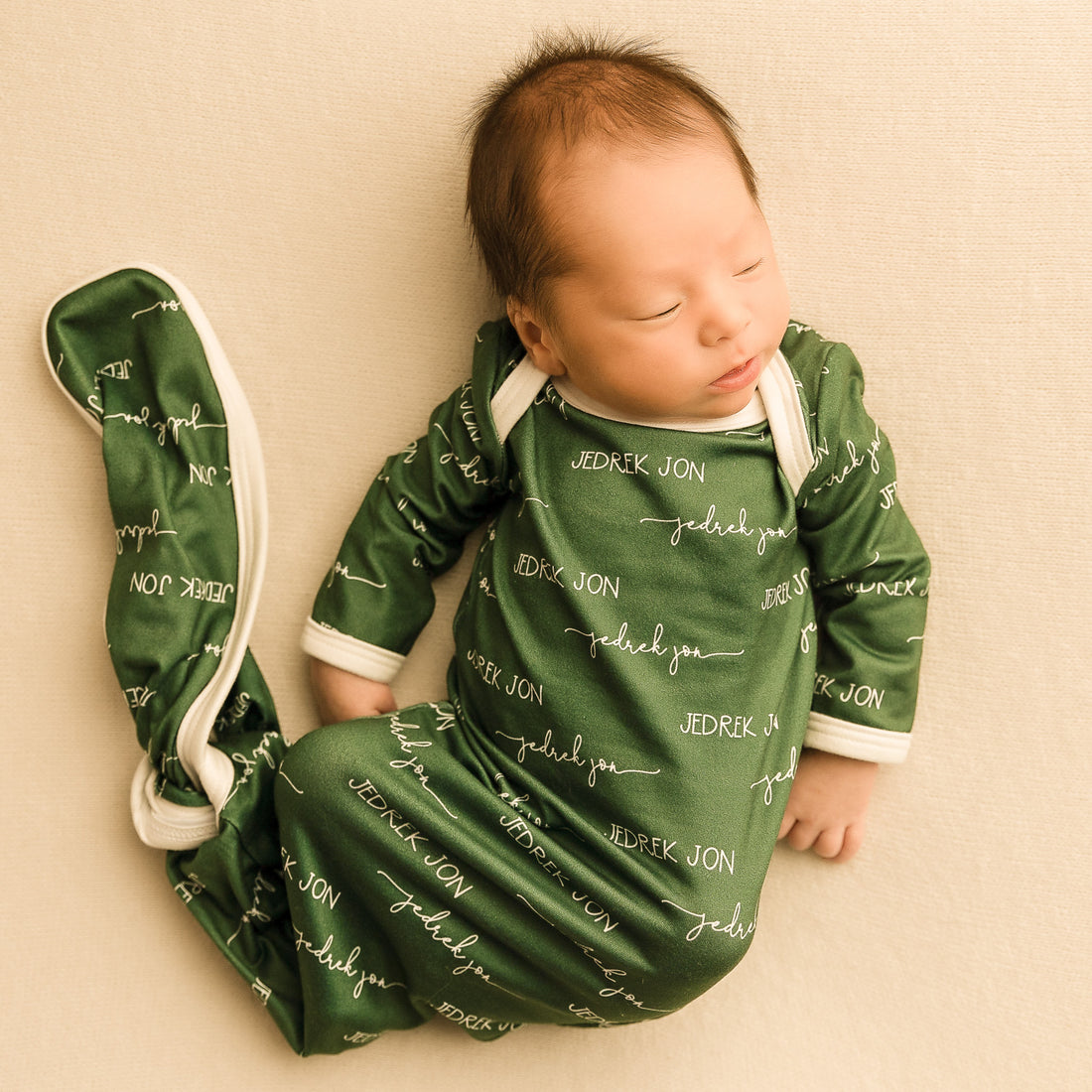 A baby sleeping in a camden olive green baby gown.