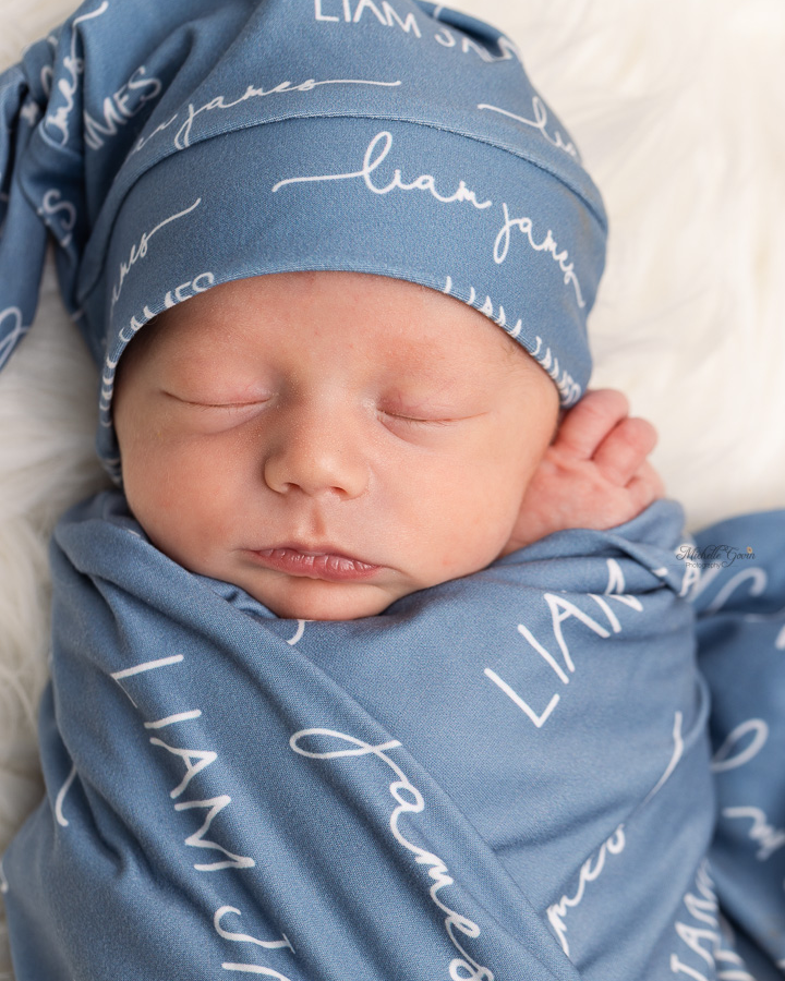 A baby peacefully sleeping swaddled in their personalized camden stretchy swaddle blanket.