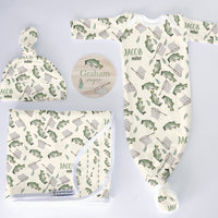 Baby clothing set with hat, blanket, and onesie featuring fish patterns on a light gray background.