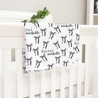 A white crib with a black and white patterned blanket featuring the name "Rachel" and the name " Michelle" printed on it.