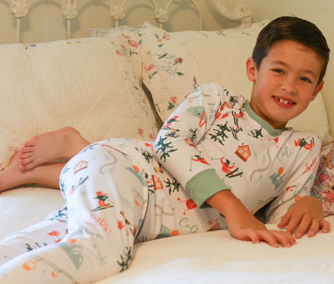 Young boy laying down wearing Ski Pajamas.