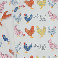 personalized chicken pajamas with a  calico design in various colors, her name in script font on a white knit background, and pink cuffs.