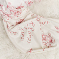a close-up view of a white fabric with a floral pattern, featuring the name 'Cara' written in cursive script.