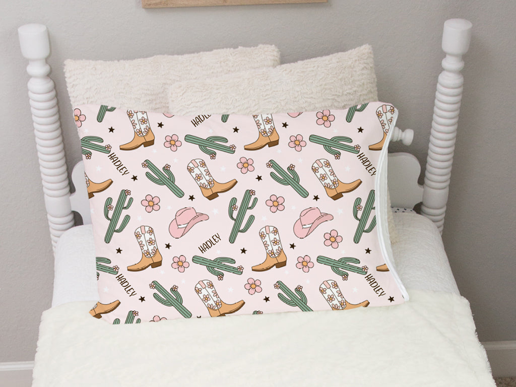 personalized cowgirl pillowcase with minky pale pink background, pink cowgirl hats, cacti, and western boots with kid's name and flowers