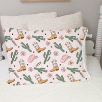 personalized cowgirl pillowcase with minky pale pink background, pink cowgirl hats, cacti, and western boots with kid's name and flowers