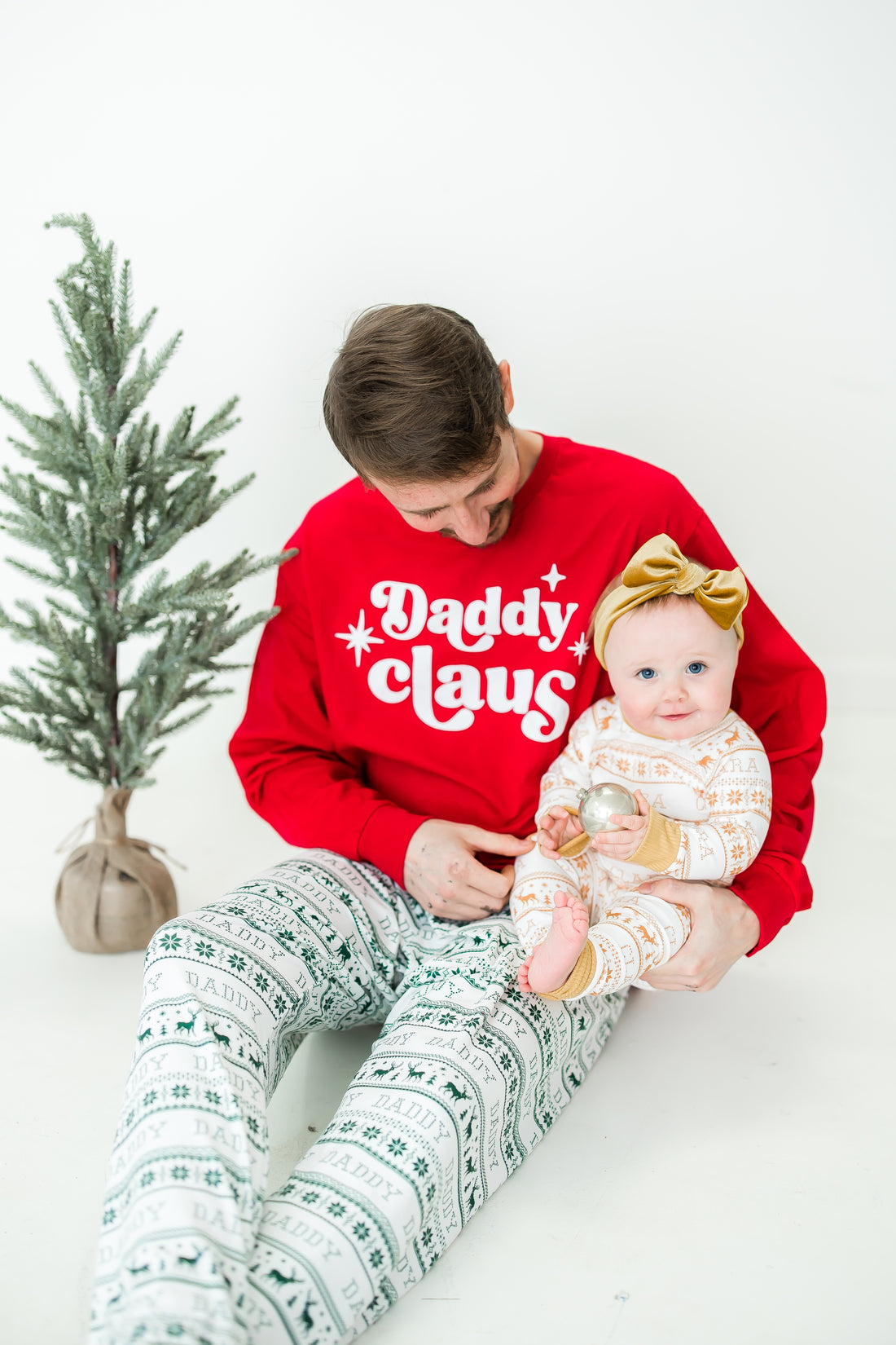 Dad and daughter wearing matching striped Christmas pajamas.