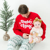Dad and daughter wearing matching striped Christmas pajamas.