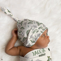 Baby wearing a fishing-patterned hat and matching swaddle with name