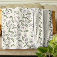 Baby blanket with bear pattern on a couch with a teddy bear and plant