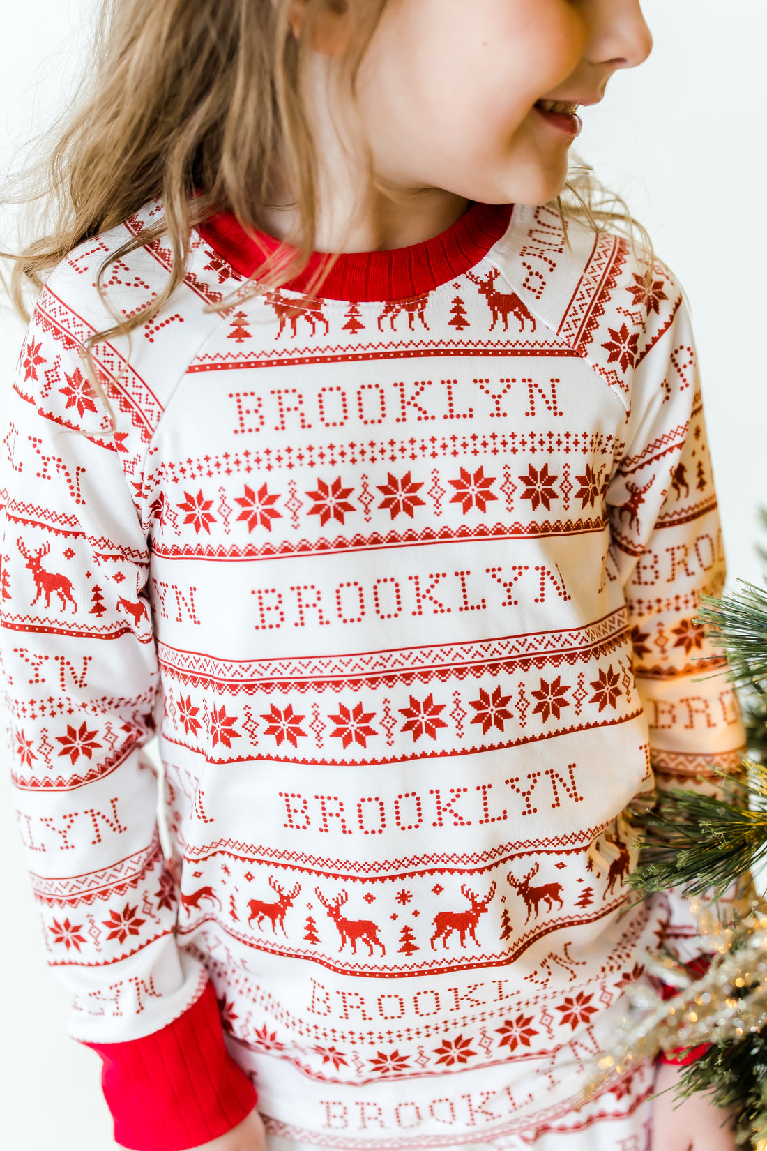 Young girl wearing red striped Christmas pajamas that are personalized with her name on them.