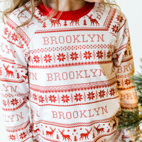 Young girl wearing red striped Christmas pajamas that are personalized with her name on them.