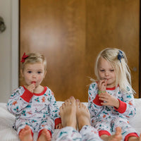 Two young girls wearing cute matching hot cocoa Christmas pajamas.