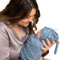 A mother holding her baby swaddled in their personalized camden stretchy swaddle blanket.