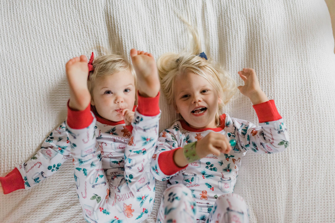Two kids posing wearing matching personalized christmas hot chocolate pajamas.