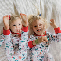 Two kids posing wearing matching personalized christmas hot chocolate pajamas.