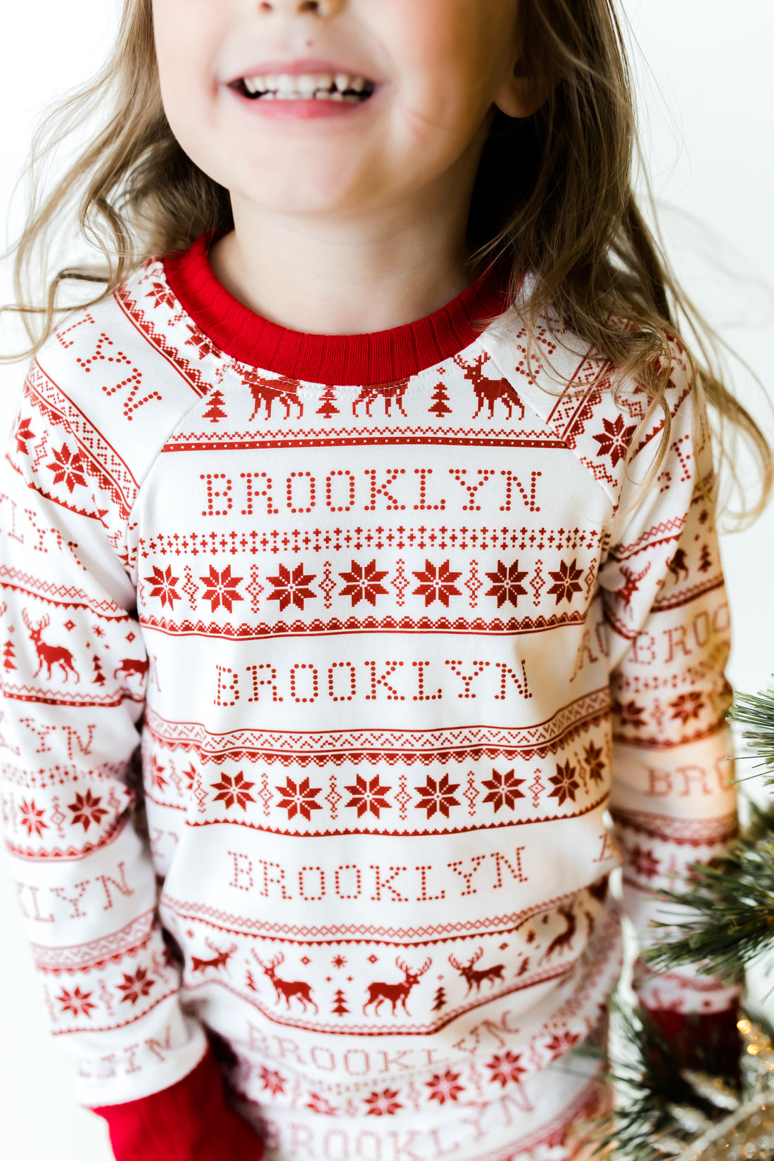Little girl wearing personalized  red striped Christmas pajamas with her name on it.