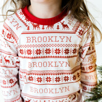 Little girl wearing personalized  red striped Christmas pajamas with her name on it.