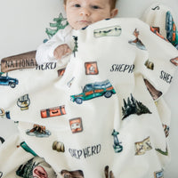 baby holding receiving blanket with his name and classic National Park themed images on a white background