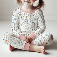 little girl wearing SIlly Goose personalized pajamas, white background stretchy knit PJs with geese and flowers. Light pink cuffs