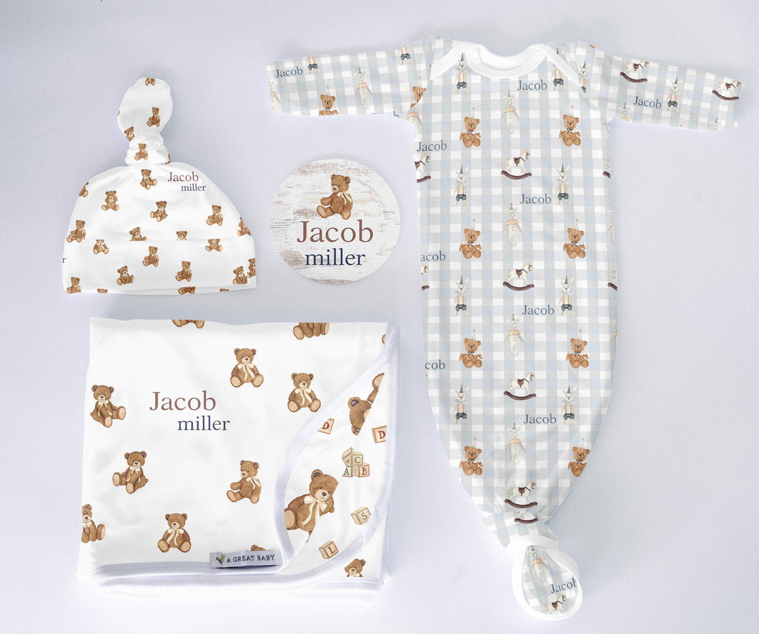 Baby clothing set with hat, blanket, and onesie featuring teddy bear pattern on a light gray background.