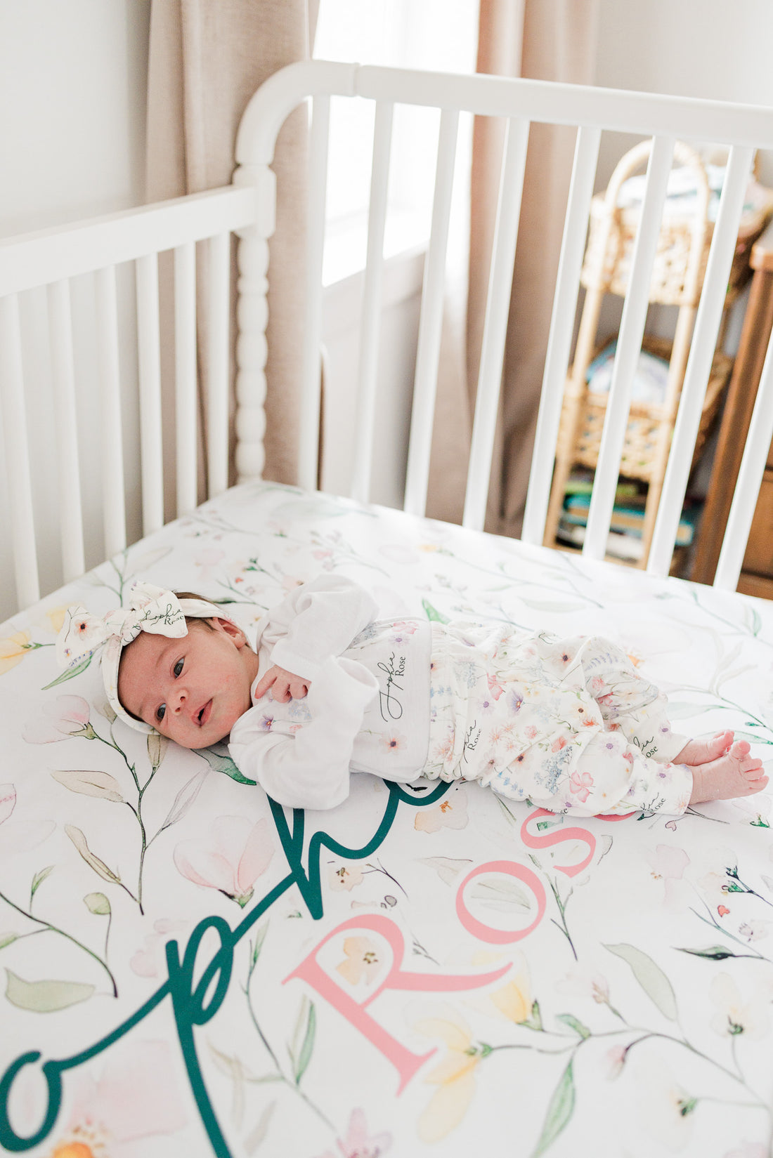 Baby girl on wildflower print personalized crib sheet, dainty wildflowers and baby's name on high-end luxury nursery bedding.
