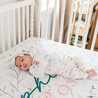 Baby girl on wildflower print personalized crib sheet, dainty wildflowers and baby's name on high-end luxury nursery bedding.