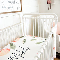 White iron bed in newborn nursery with an ivory custom crib sheet for baby bedding. Personalized with name of child in middle